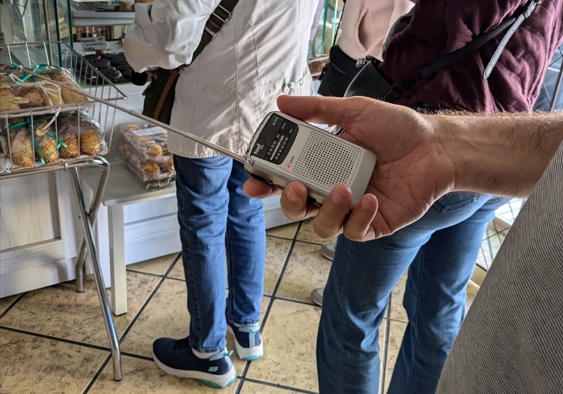 Una radio recién estrenada en la cola de una panadería sujeta por su dueño, que intenta comprar unos últimos dulces de emergencia.