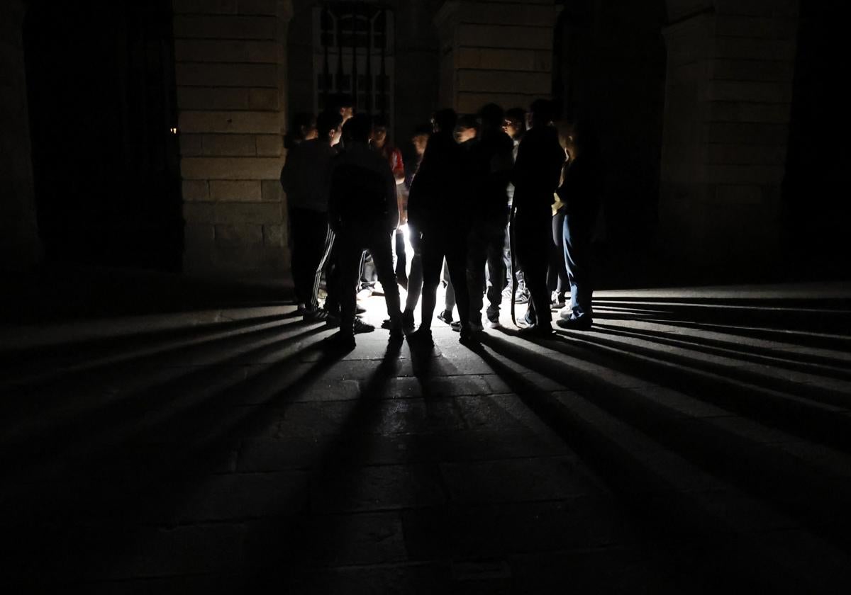 Jóvenes se reúnen frente a una catedral durante un apagón este martes, en Santiago de Compostela.