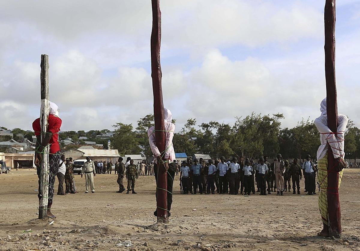 Tres hombres atados a postes esperan a ser ejecutados por un pelotón de fusilamiento en Somalia.