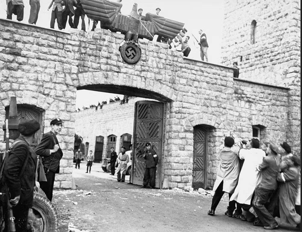 Supervivientes españoles desmontan el águila nazi que cuelga sobre la entrada del recinto de las SS en Mauthausen el día de la liberación. Foto: Museo del Holocausto.