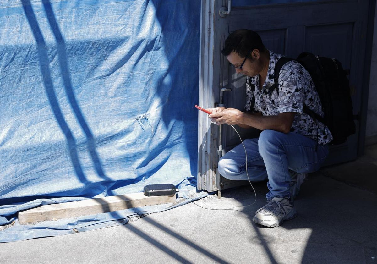 Un joven carga su móvil con una batería solar
