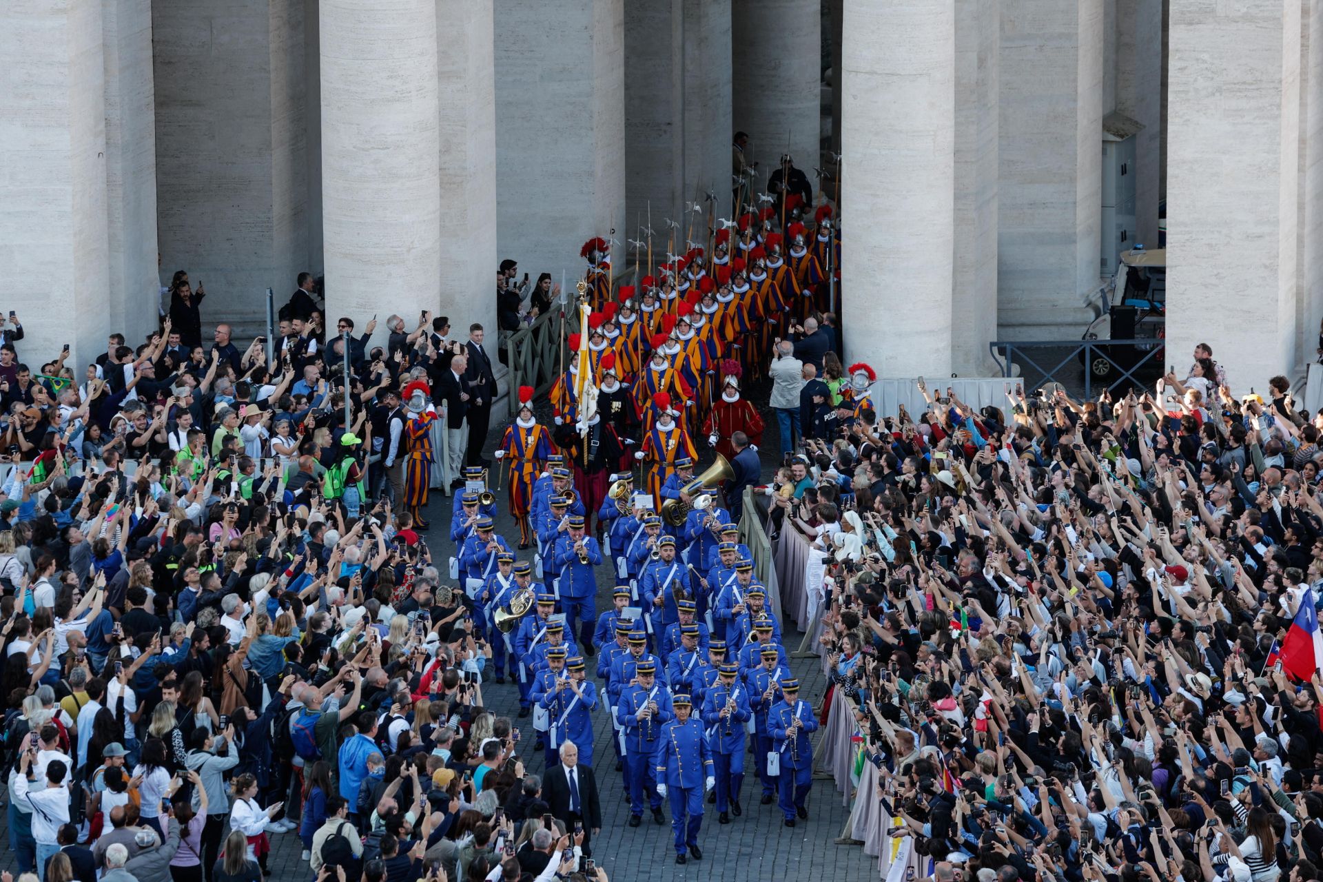 Imagen secundaria 2 - En la imagen superior, los fieles jalean a León XIV tras su discurso; debajo, un religioso porta con alegría la bandera estadounidense; por último, la Guardia Suiza sale hacia la basílica. 