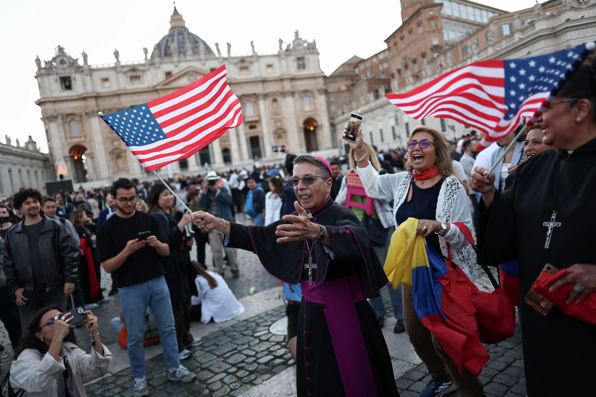 Imagen secundaria 1 - En la imagen superior, los fieles jalean a León XIV tras su discurso; debajo, un religioso porta con alegría la bandera estadounidense; por último, la Guardia Suiza sale hacia la basílica. 