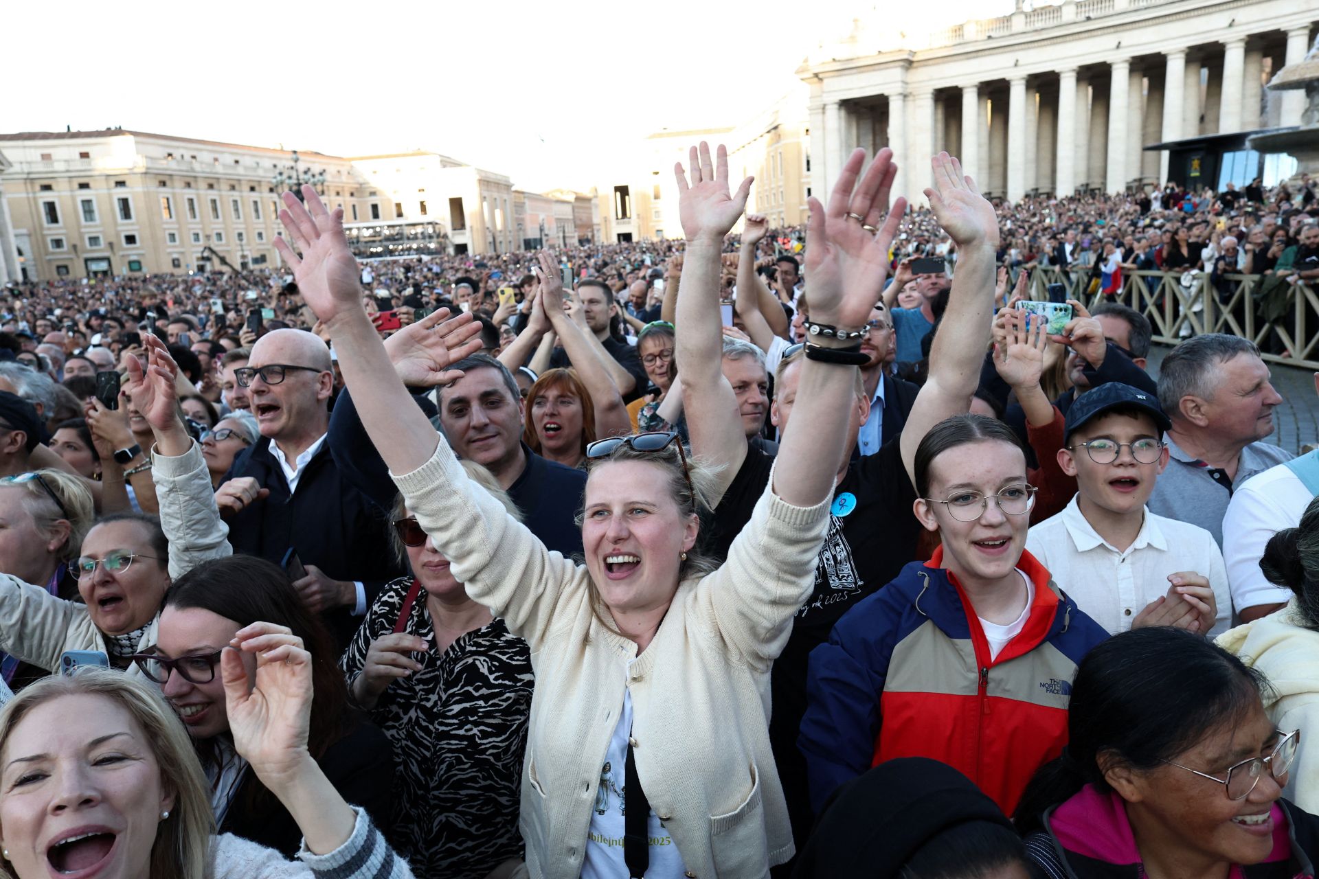 Imagen principal - En la imagen superior, los fieles jalean a León XIV tras su discurso; debajo, un religioso porta con alegría la bandera estadounidense; por último, la Guardia Suiza sale hacia la basílica. 
