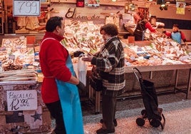 Una mujer recoge su compra en la pescadería.