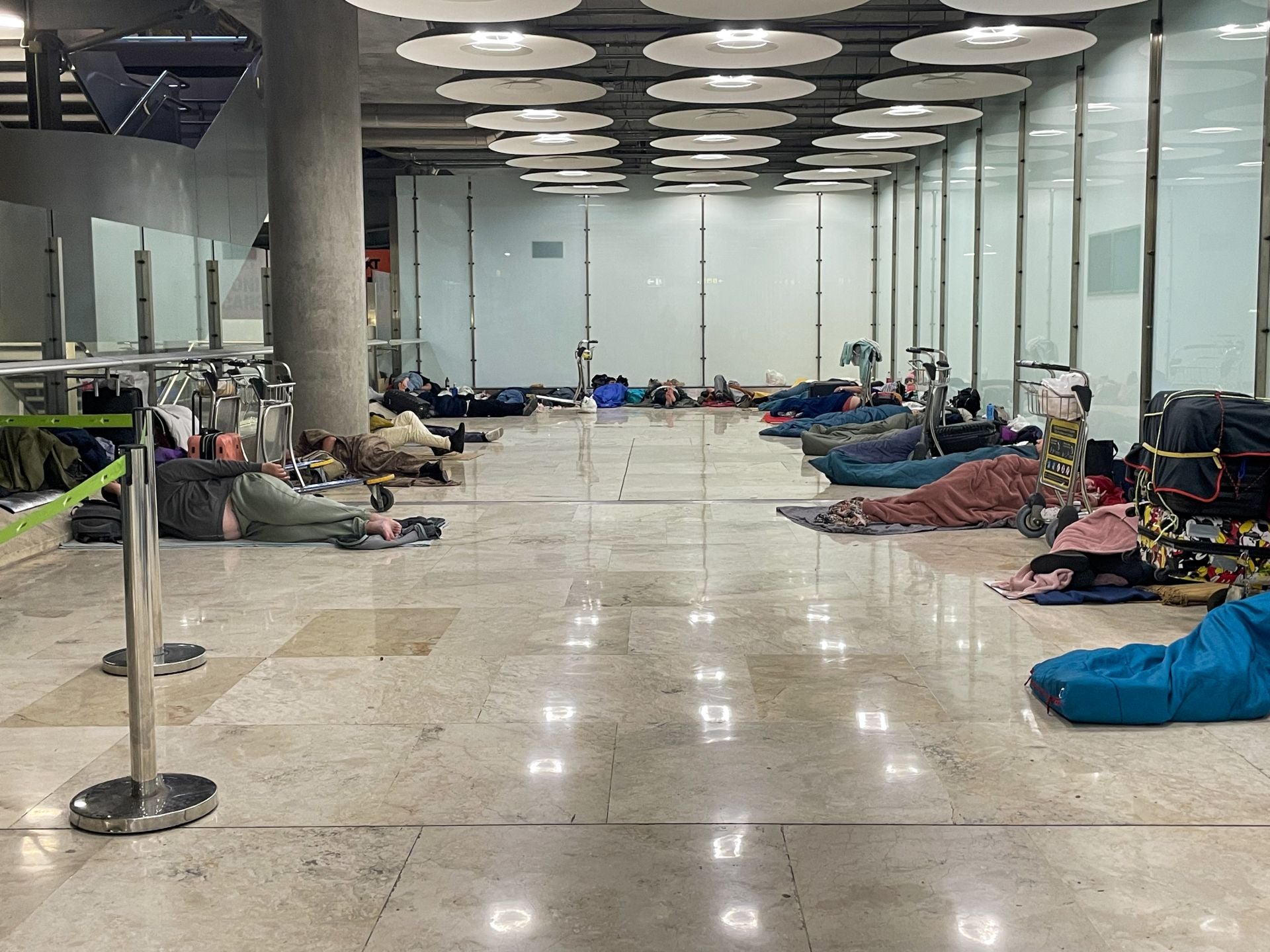 Un grupo de personas descansa en los pasillos de la T4 en mitad de la madrugada.