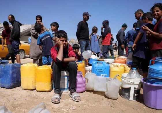 Familias con niños hacen cola para recoger agua en un campamento para desplazados en Ciudad de Gaza.