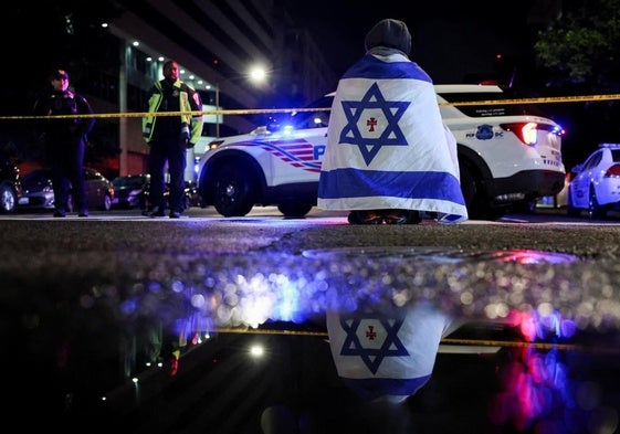 Un hombre con una bandera de Israel en el lugar donde se produjo el asesinato.