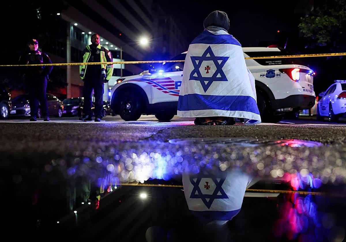 Un hombre con una bandera de Israel en el lugar donde se produjo el asesinato.