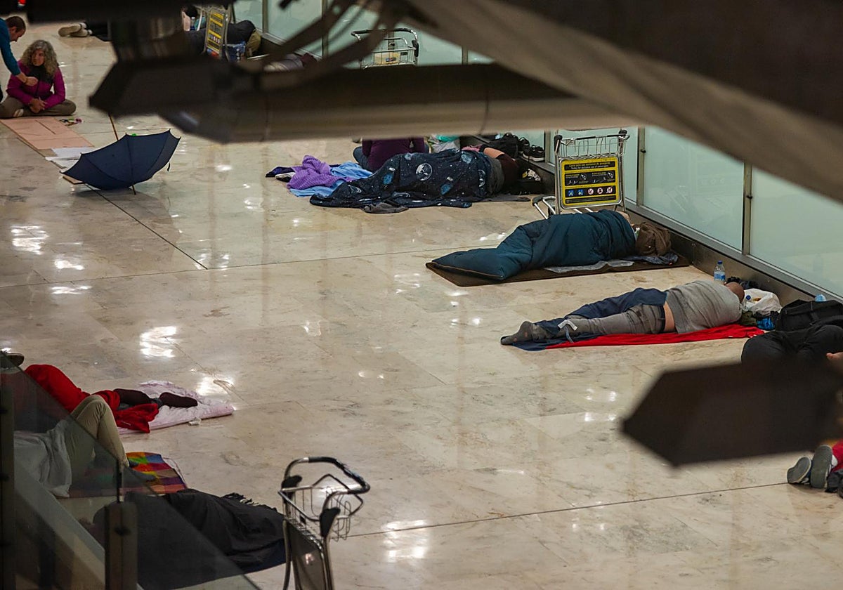 Personas sin hogar duermen en la T4 de Barajas.