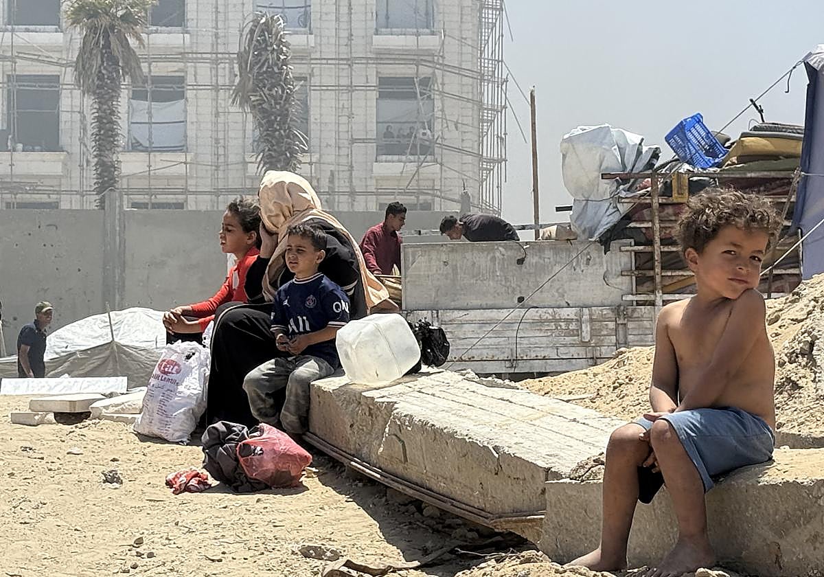 Varios niños sentados en los cascotes de las ruinas de Gaza.