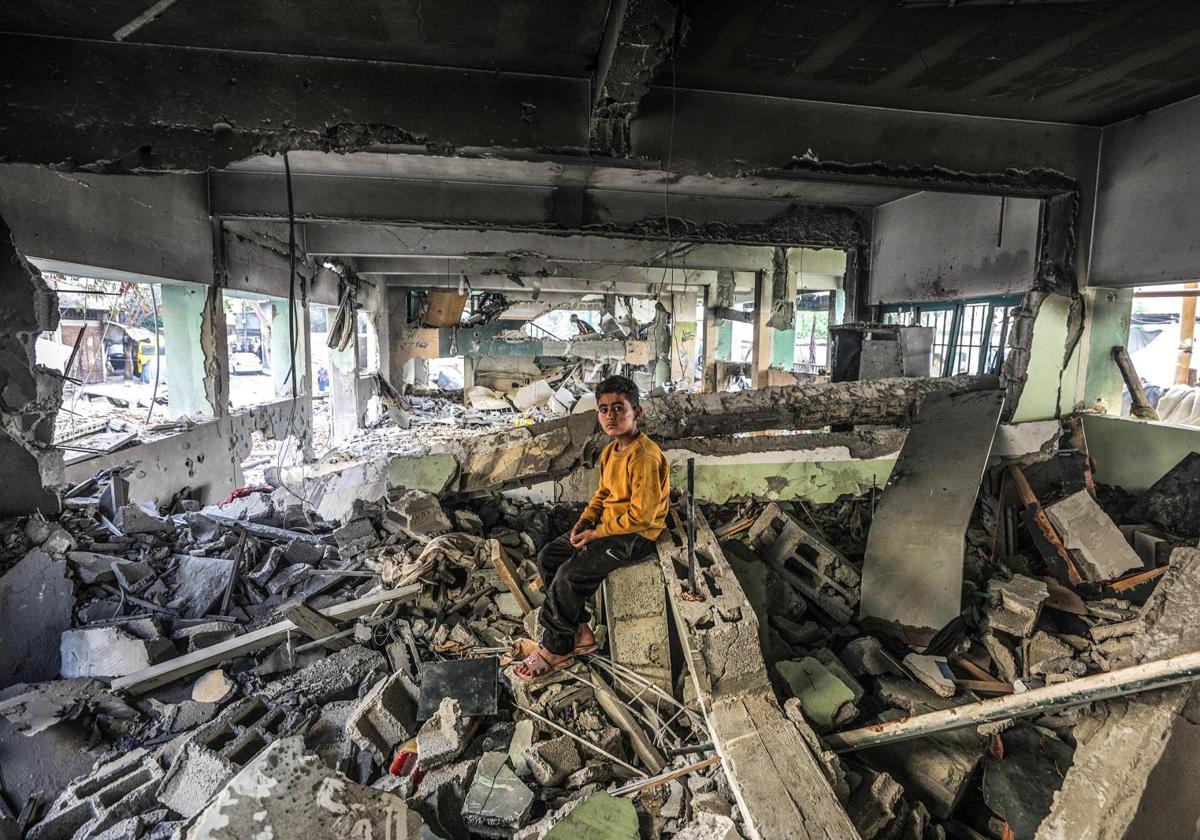 Un niño permanece sentado entre las ruinas del colegio bombardeado en Gaza City donde murieron 36 civiles, 18 de ellos menores.