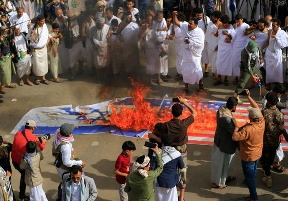 Yemeníes queman banderas de Israel y Estados Unidos durante una manifestación en solidaridad con Gaza en la capital gobernada por los hutíes, Saná.