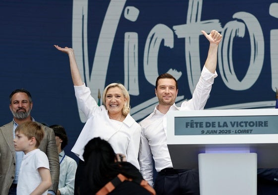 Marine Le Pen y Jordan Bardella saludan en la convención ultra, con Abascal al fondo.