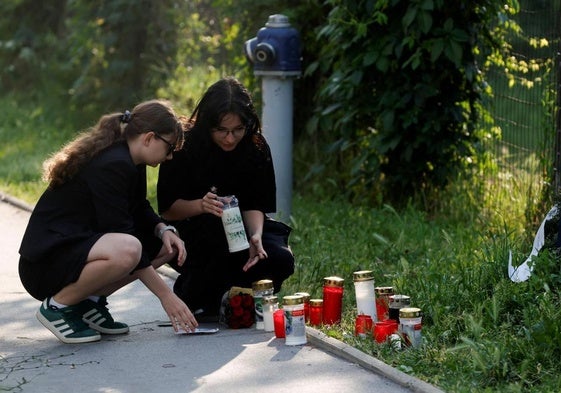 Dos estudiantes rinden homenaje a los alumnos asesinados en el exterior del colegio.