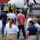 Agentes federales vigilan a migrantes antes de ser deportados de Estados Unidos a Colombia.