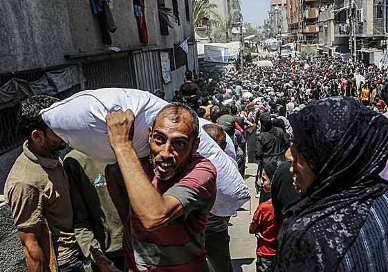 Cientos de gazatíes se concentran en un centro de reparto para recibir ayuda.