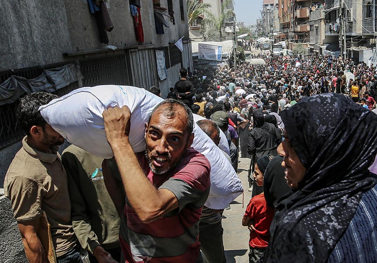 Cientos de gazatíes se concentran en un centro de reparto para recibir ayuda.