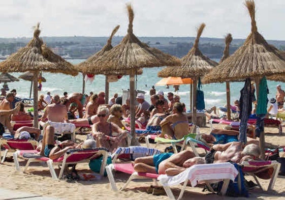 Numerosos turistas tomando el sol en una playa.