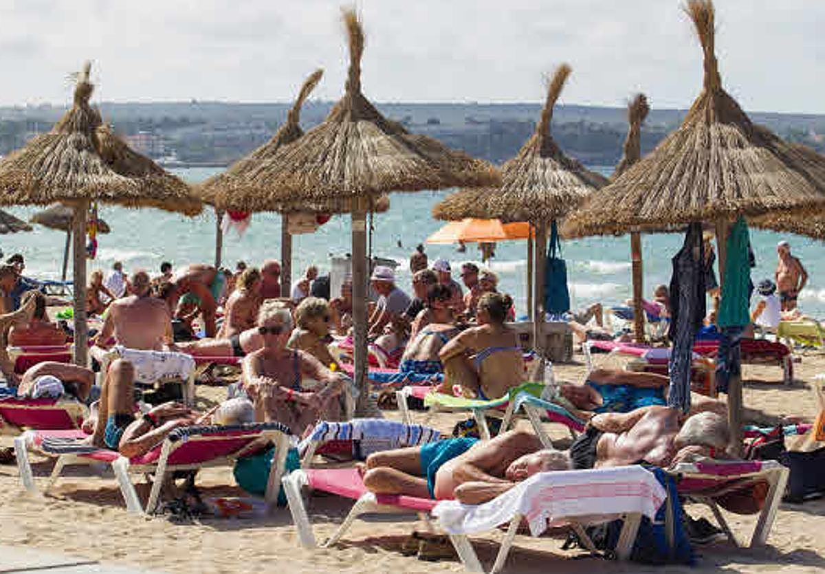 Numerosos turistas tomando el sol en una playa.
