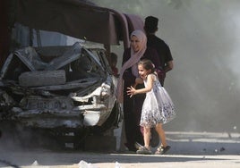 Una madre y su hija corren a refugiarse durante un ataque israelí en el campamento de Al-Bureij, en el centro de Gaza.