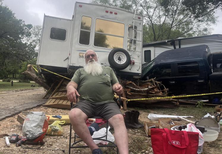 Un hombe permanece sentado delante de los restos de su autocaravana.