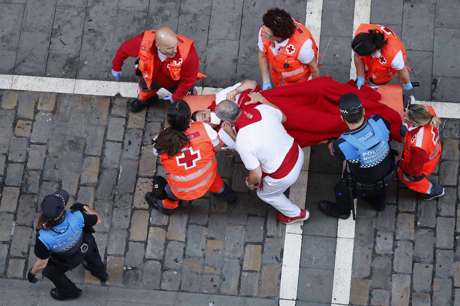 Los servicios de emergencia evacúan a uno de los corredores heridos en el cuarto encierro de los Sanfermines.