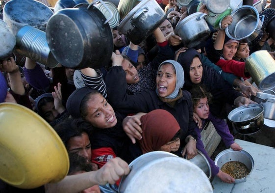 Familias palestinas se agolpan para recibir comida en Gaza.