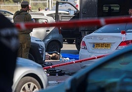 Agentes israelíes junto a un cadáver en la escena de un atentado en un centro comercial de un asentamiento hebreo en Gush Etzion, Cisjordania.