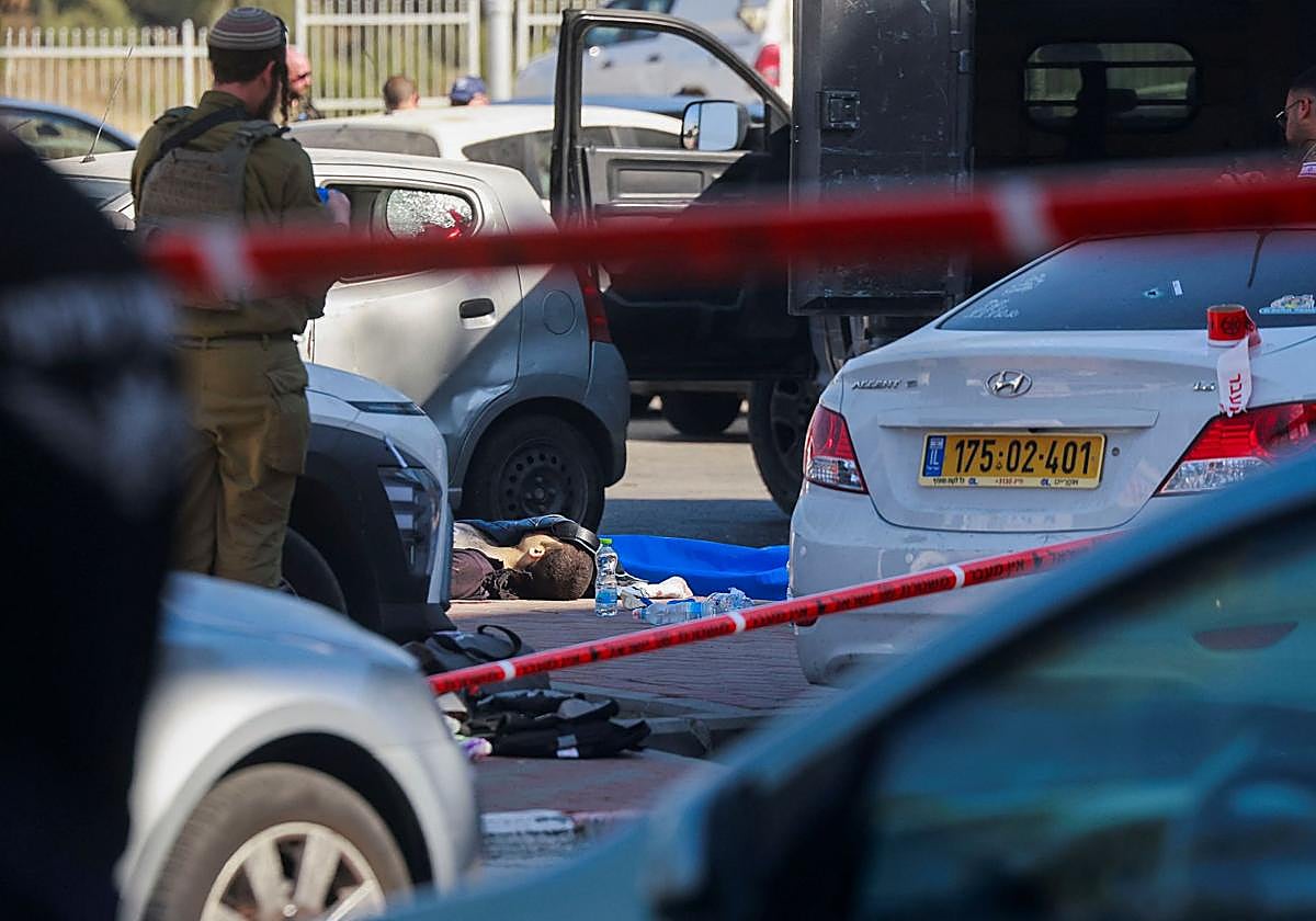 Agentes israelíes junto a un cadáver en la escena de un atentado en un centro comercial de un asentamiento hebreo en Gush Etzion, Cisjordania.
