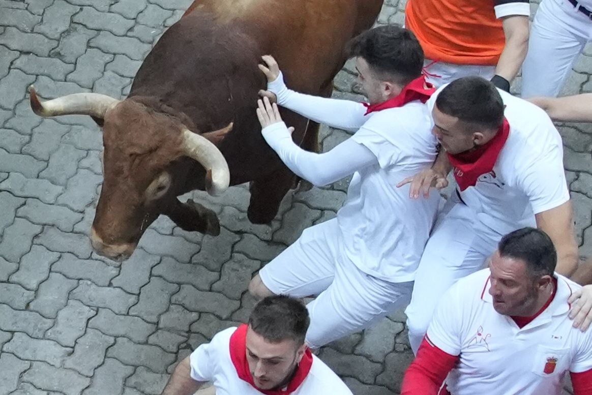 Un mozo tropieza ante uno de los toros de la ganadería Jandilla durante el quinto encierro de los Sanfermines este viernes en Pamplona.