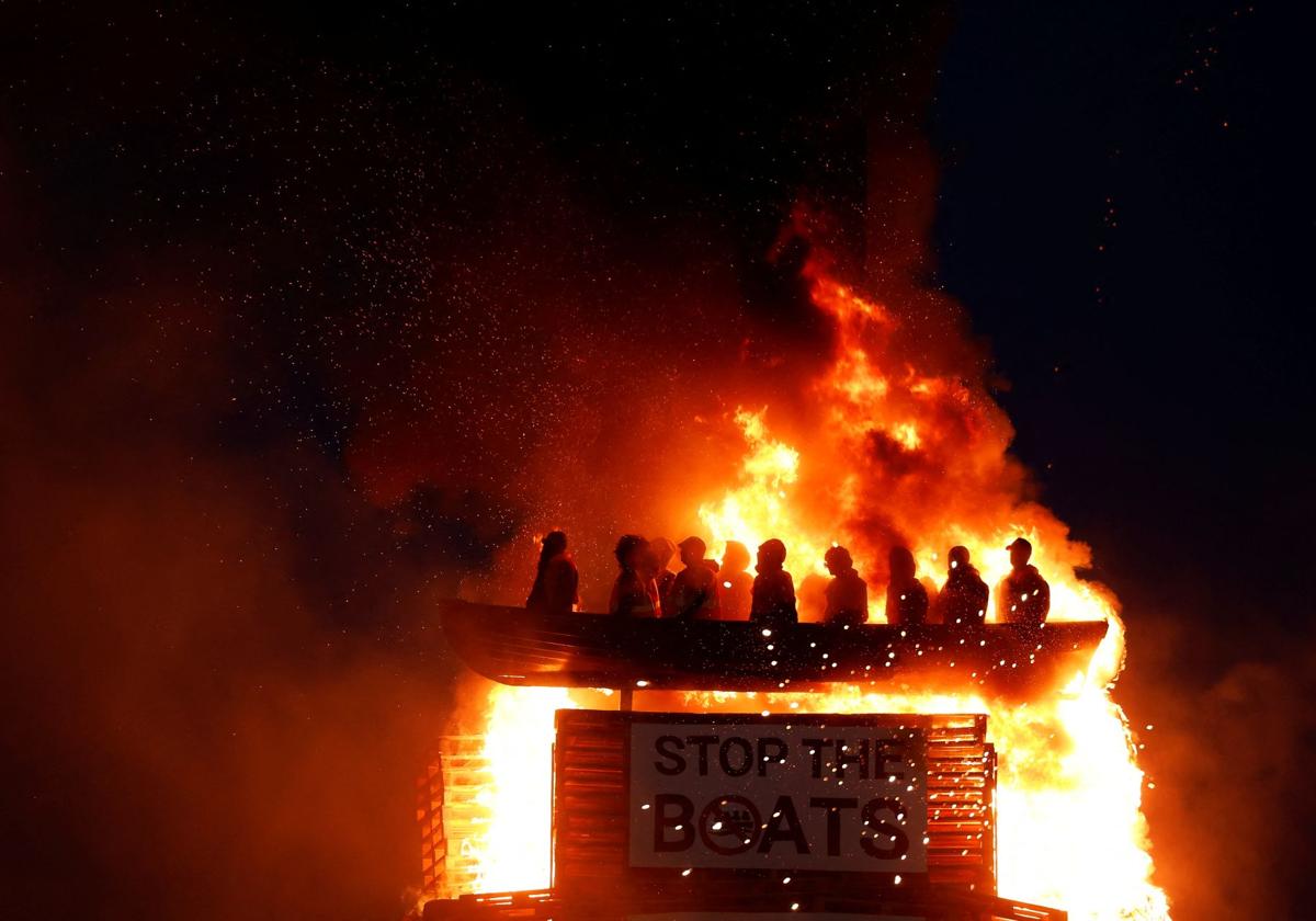 Arde una hoguera con muñecos de migrantes en una patera, en Moygashel.