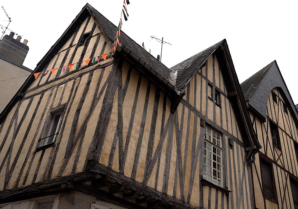 Imagen principal - Arriba, casas de entramado de madera, típicas del casco medieval. A la izquierda, una mujer observa varias obras en el Museo de Arte Naif y Artes Singulares ubicado en el castillo de Laval. A la derecha, la puerta Beucheresse, en cuya torre nació el pintor naíf Henri Rousseau.