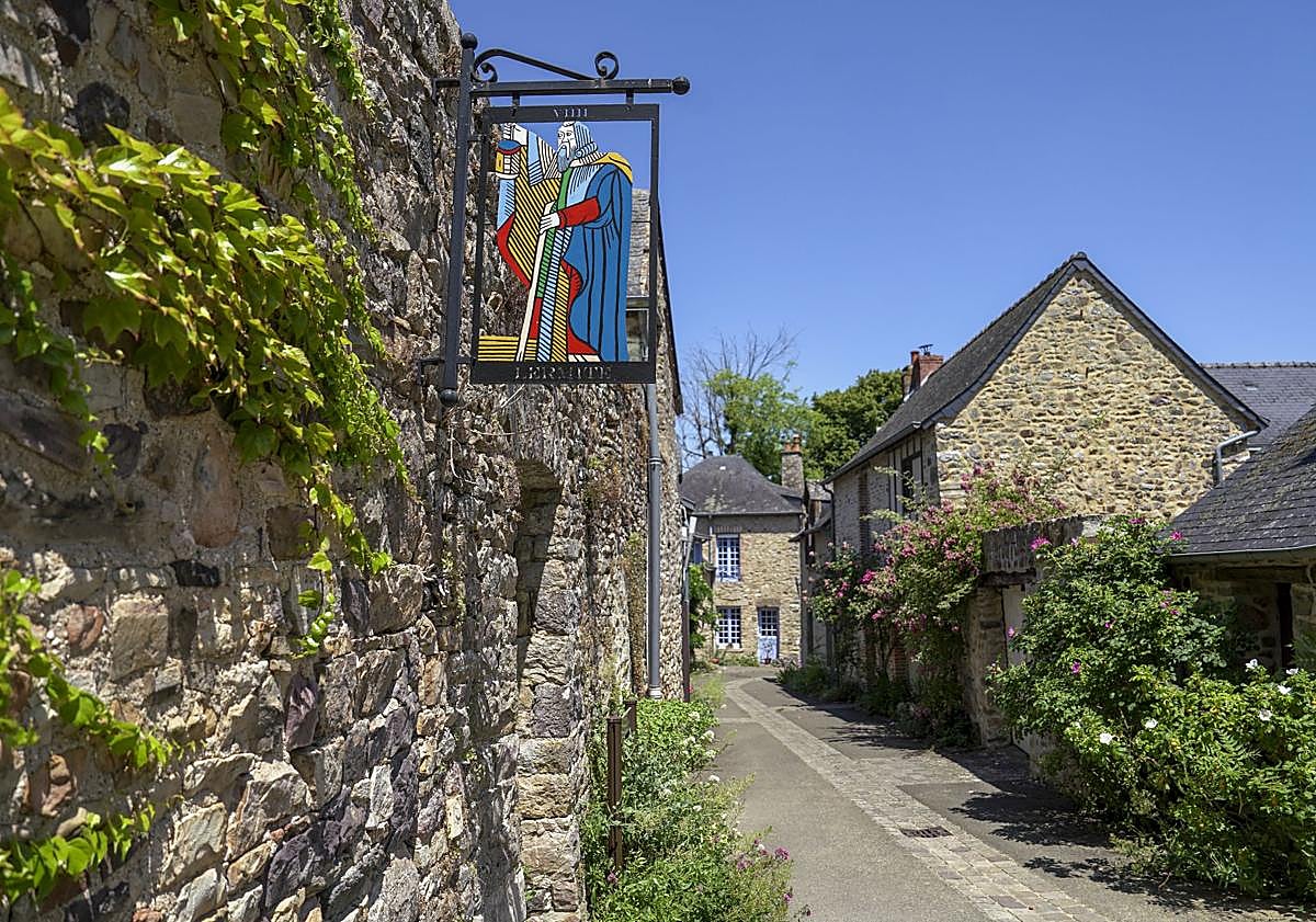 Imagen principal - Arriba, detalle de un letrero con una figura de las cartas del tarot. A la izquierda, vistas del pueblo desde lo alto del castillo. A la derecha, la senda extramuros conocida como 'le promenade de la Poterne' que rodea el pueblo de Sainte Suzanne.