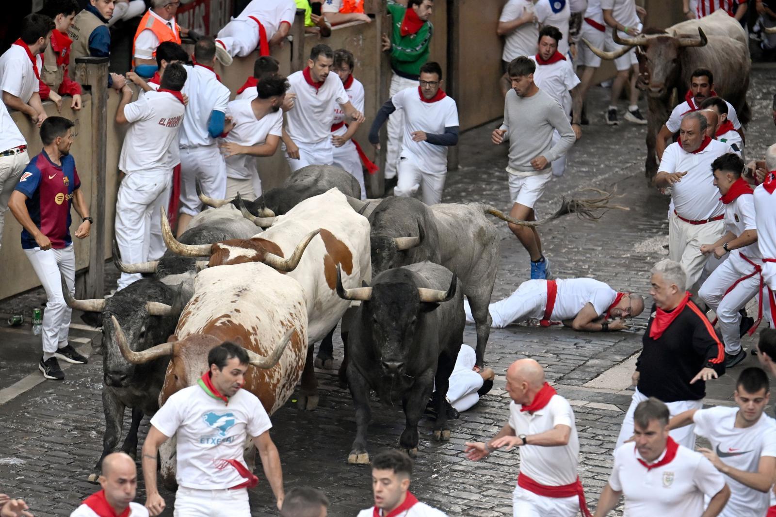 Varios corredores caen al suelo delante de los toros.