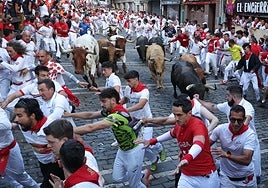 Los toros de la ganadería Jandilla persiguen a los mozos a su paso por la curva de Mercaderes durante el quinto encierro de los Sanfermines este viernes en Pamplona.