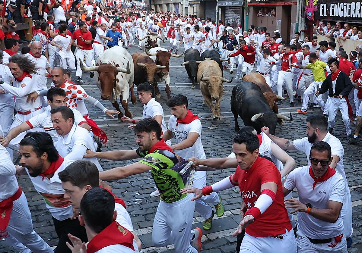 Los toros de la ganadería Jandilla persiguen a los mozos a su paso por la curva de Mercaderes durante el quinto encierro de los Sanfermines este viernes en Pamplona.