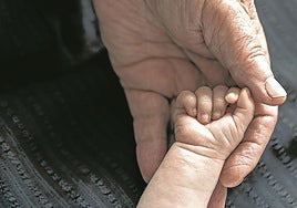 Un abuelo coge la mano de su nieto.