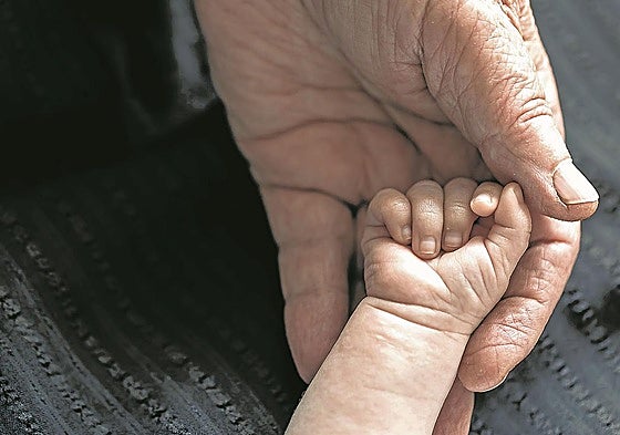 Un abuelo coge la mano de su nieto.