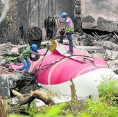 Trabajadores indios retiran los restos del avión de Air India con ayuda de una grúa en el lugar del accidente, en Ahmedabad.