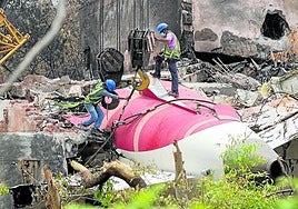 Trabajadores indios retiran los restos del avión de Air India con ayuda de una grúa en el lugar del accidente, en Ahmedabad.