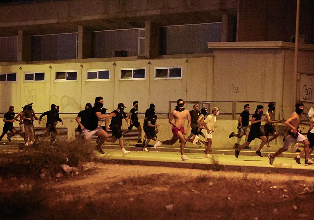 Grupo de gente huye de los agentes policiales, en medio de protestas antimigrantes.
