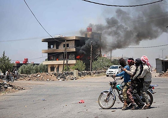 Combatientes tribales observan una vivienda en llamas en la localidad siria de Sueida.