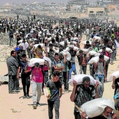 Ciudados de Gaza cargan a hombros con sacos de comida en un centro de reparto.