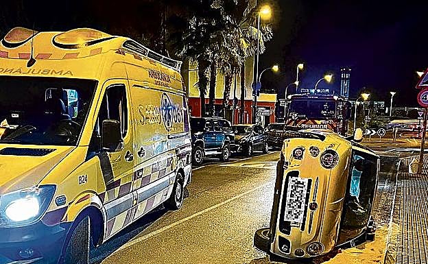 Una ambulancia acude a auxiliar al conductor un coche volcado.