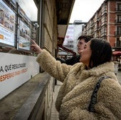 Dos jóvenes mirando anuncios de viviendas que se venden o alquilan.