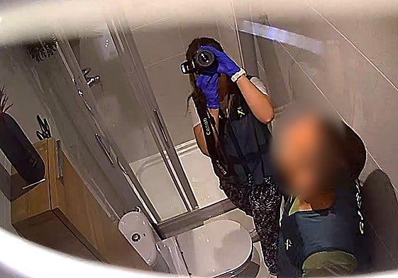 Punto de vista de la cámara oculta muestra agentes de la Guardia Civil investigando el baño.