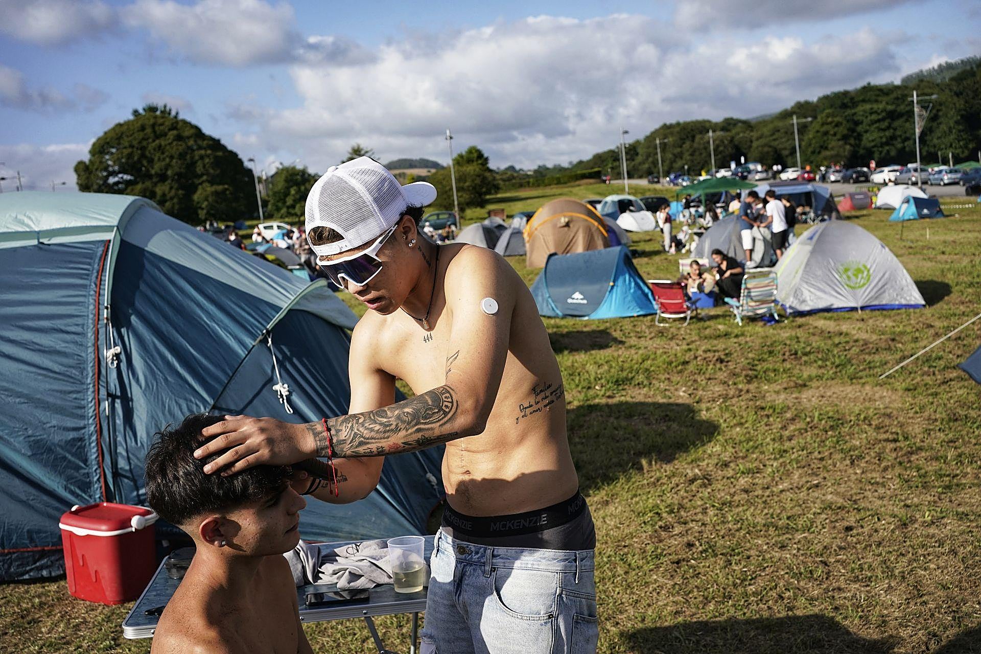 Osvaldo Herrera, de Ferrol, corta el pelo a un amigo en la zona de acampada.