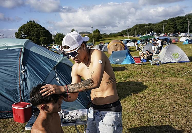 Osvaldo le corta el pelo a un amigo en la zona de acampada.