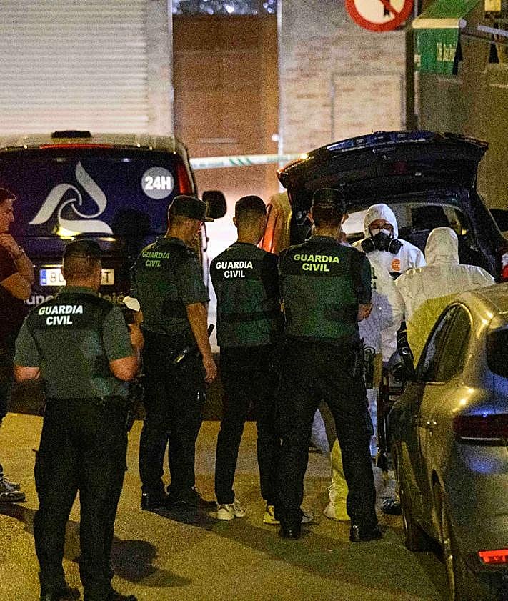 Imagen secundaria 2 - Arriba, la puerta de la casa donde se encontró el cadáver. Abajo, agentes en la entrada del edificio.